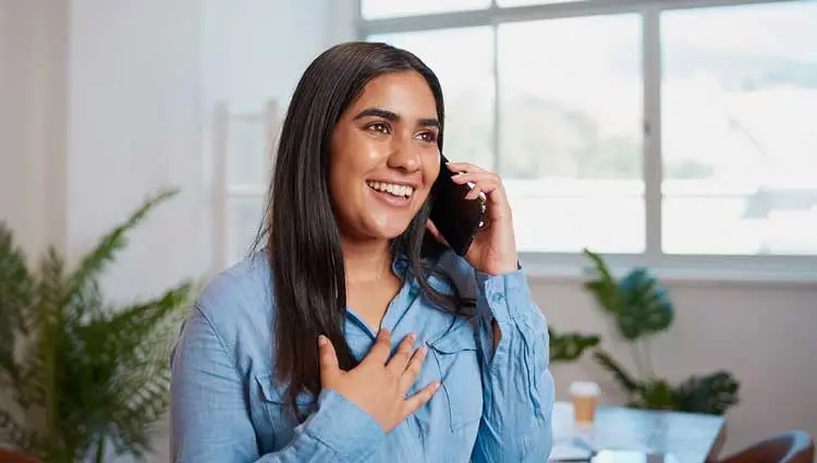 Smiling woman speaking on the phone in a bright office, expressing gratitude or excitement for agift made to her nonprofit.